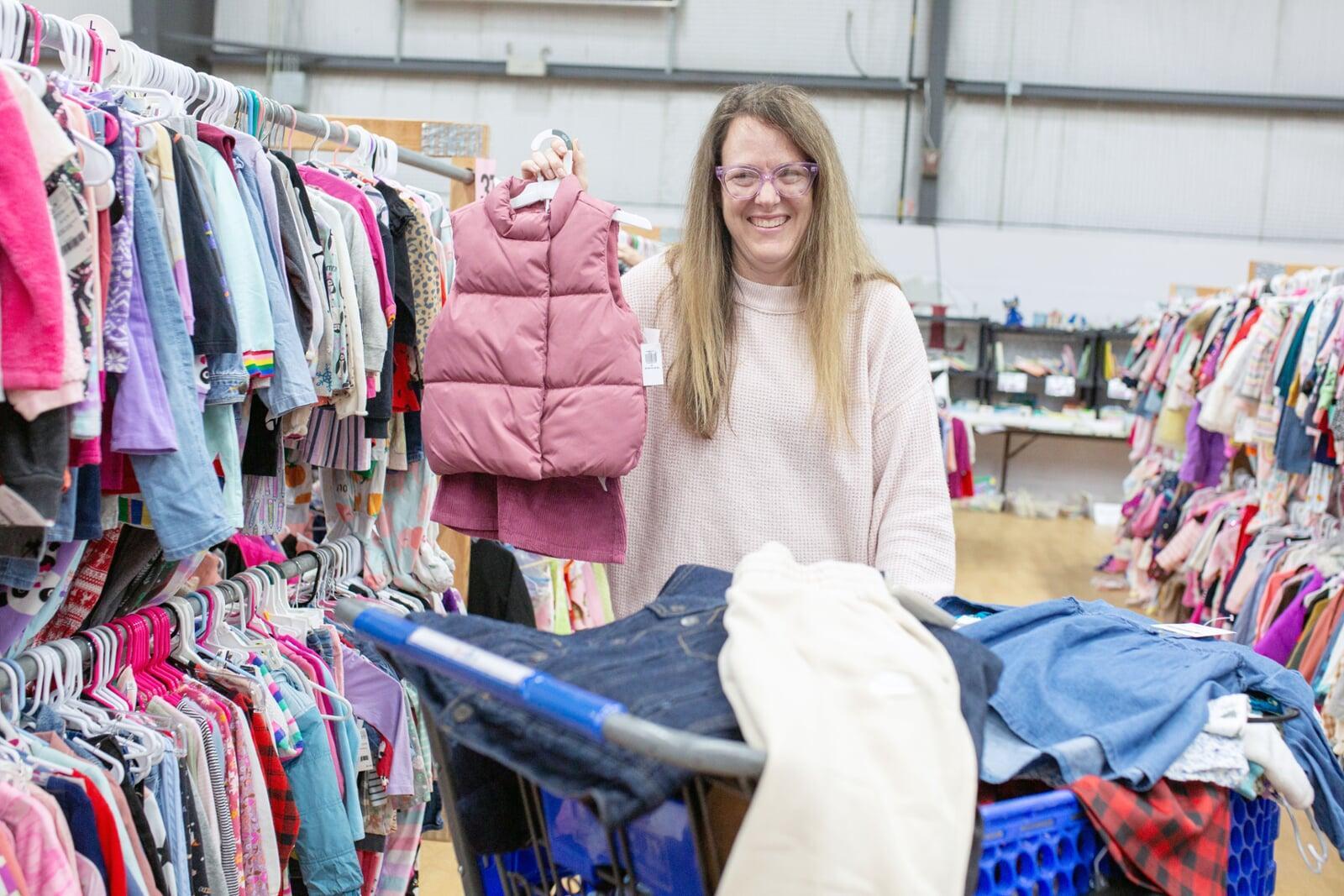 A mom and grandmother stand beside a rack of clothing at a JBF sale in Texas.