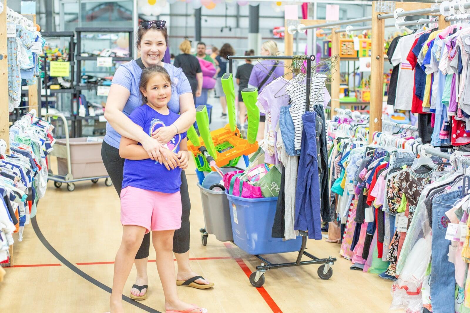 A mom and her two kids stand in the shoe section for a happy family photo.