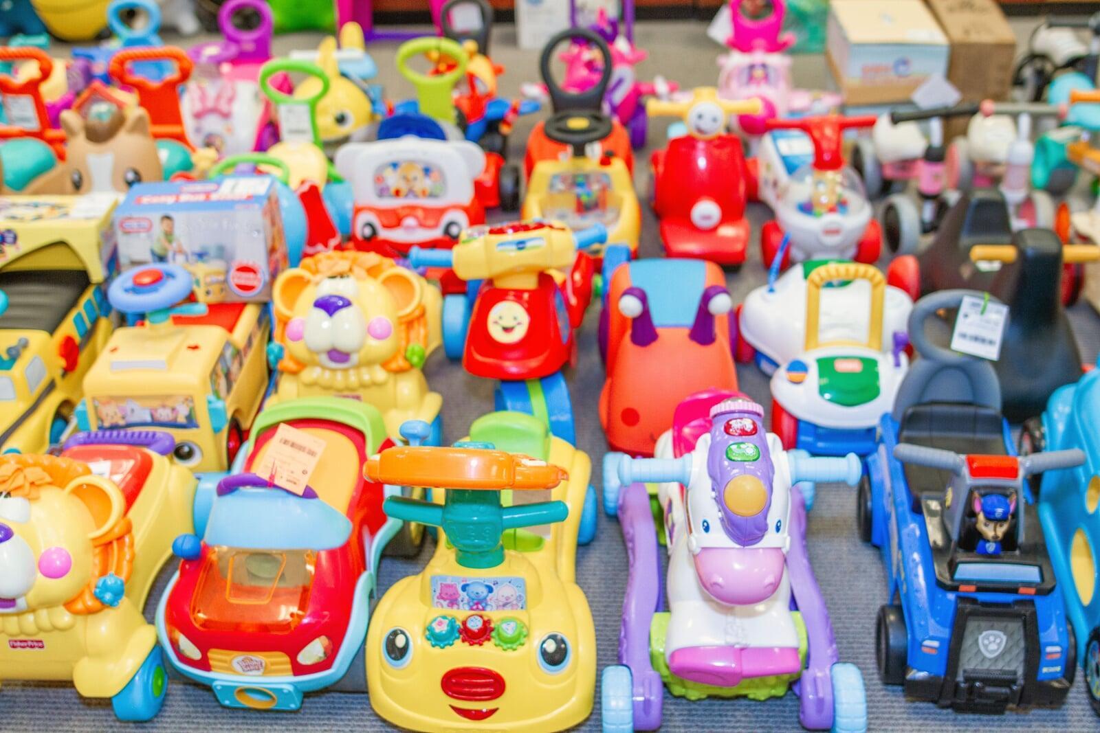 Tricycles, scooters and toys lined up on a table waiting for shoppers to attend the sale.